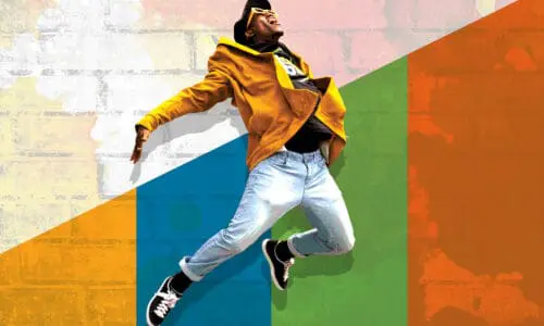 Joyous young man leaping in the air, against the backdrop of a brick wall with gold, teal, green and orange overlay.