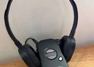 An Assistive Listening Device leaning upright on a pair of black over-ear headphones.