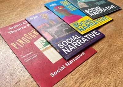 Four booklets that all read "SOCIAL NARRATIVE" fanned out on a wooden table.